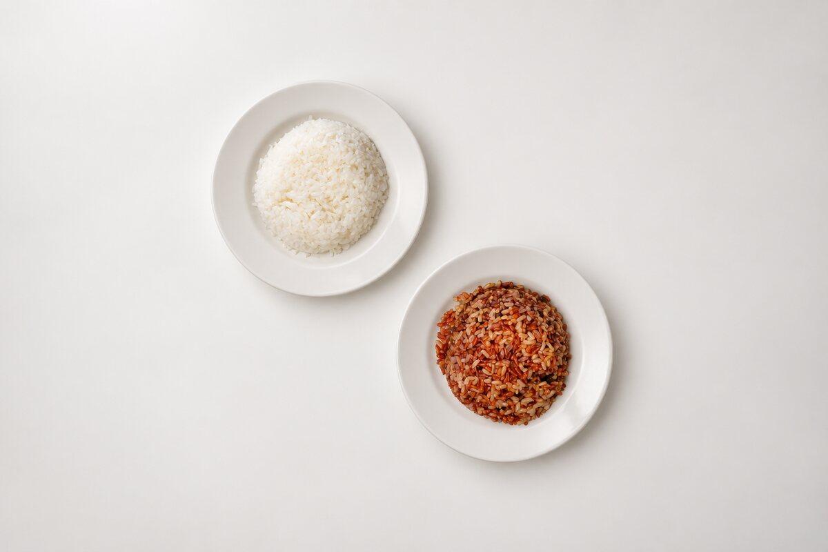 A bowl of white rice and a bowl of brown rice, seen from above.