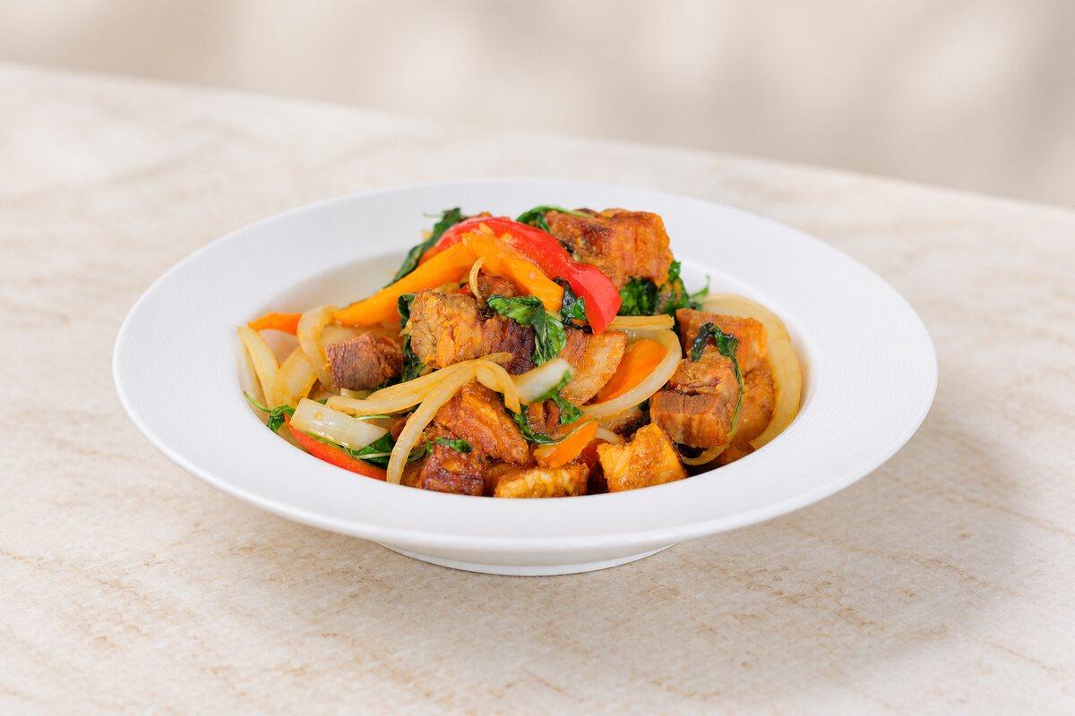 A stir-fry of meat with bell pepper and onion on a white plate.