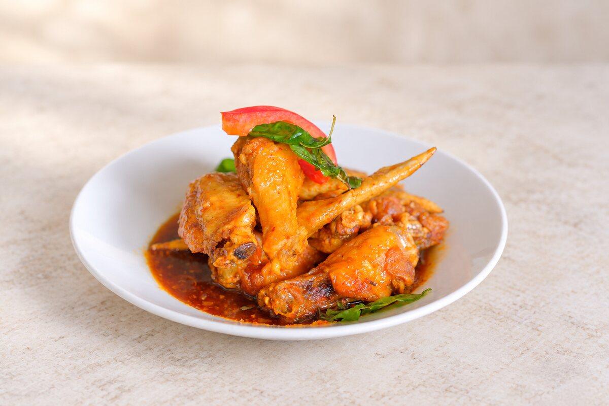 Glazed chicken wings with a red chilli and fried basil.
