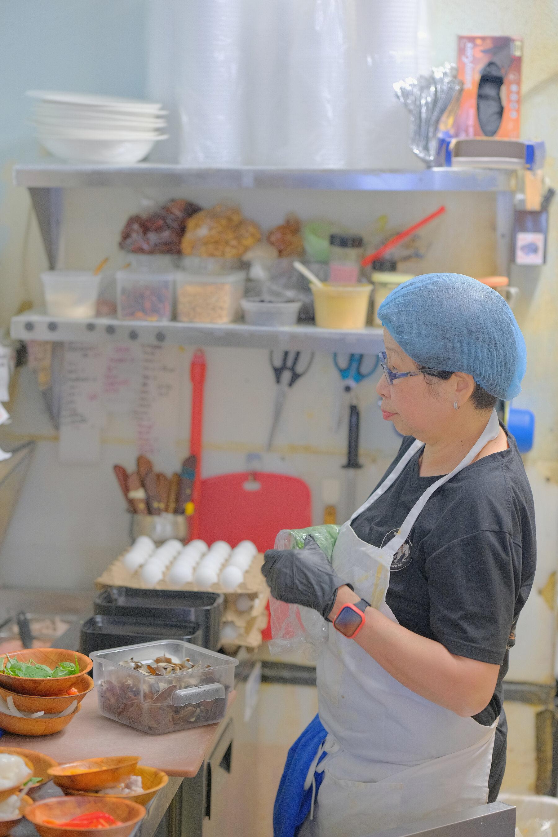 A cook at the kitchen pass, plating an order.